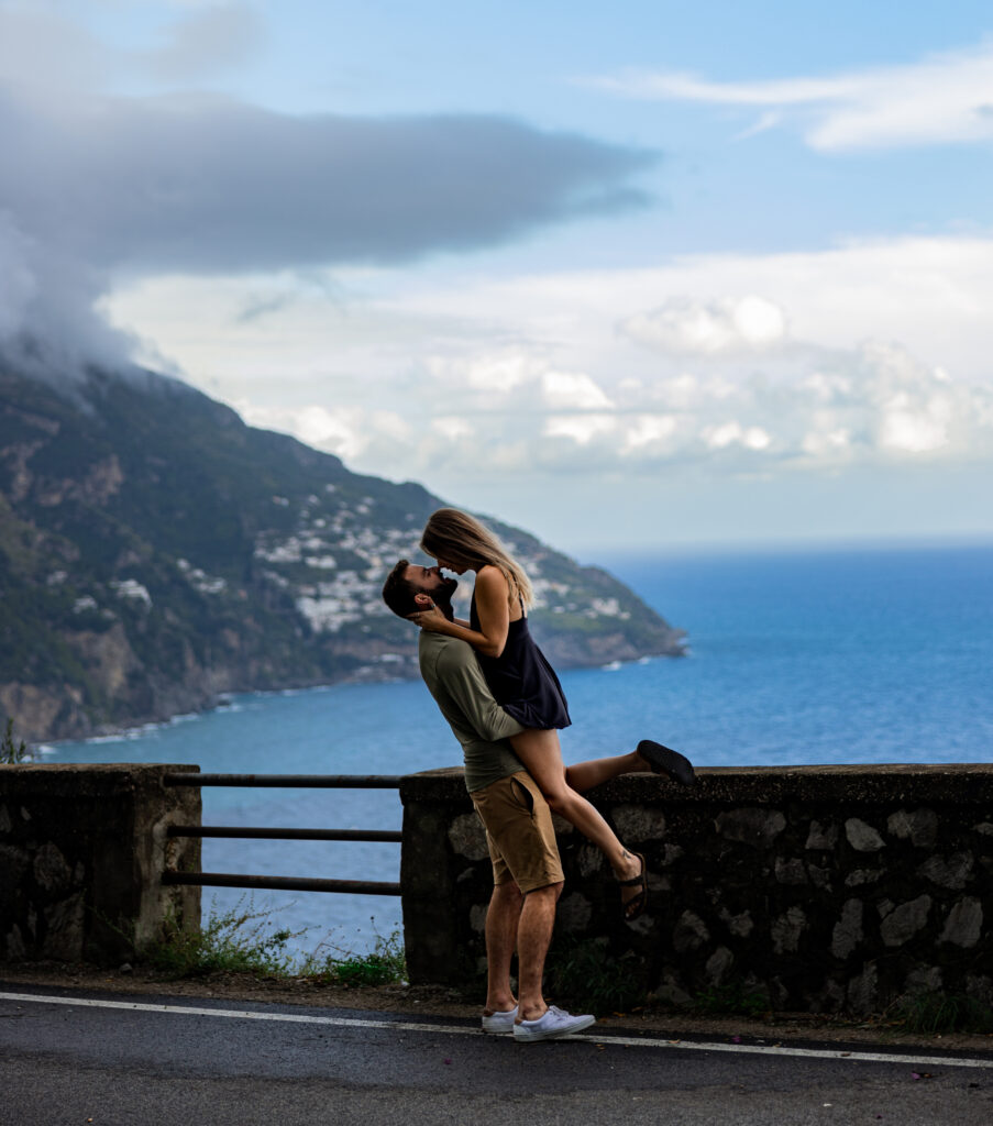 Guy lifting girl in the air on the coast of the Amalfi Coast near Positano Italy