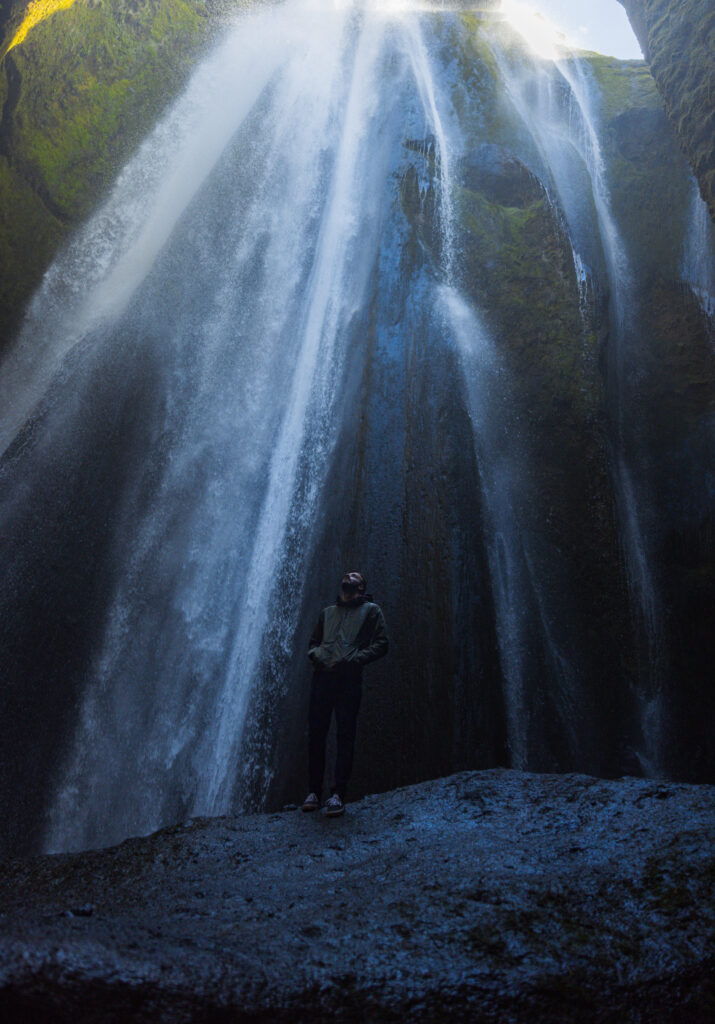 a guy looking up at Gljufrabui waterfall in Iceland