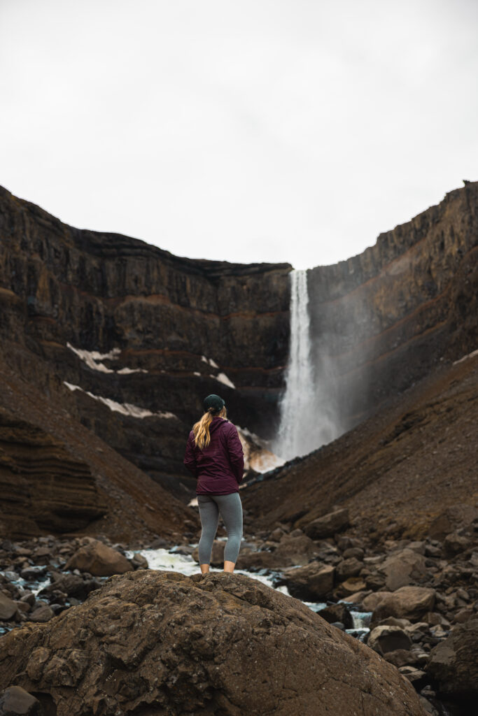 A girl looking at Hengifoss falls in Iceland