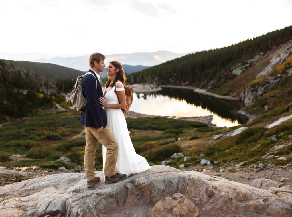 Groom wrapping his jacket around the bride to keep her warm in the mountain breeze.