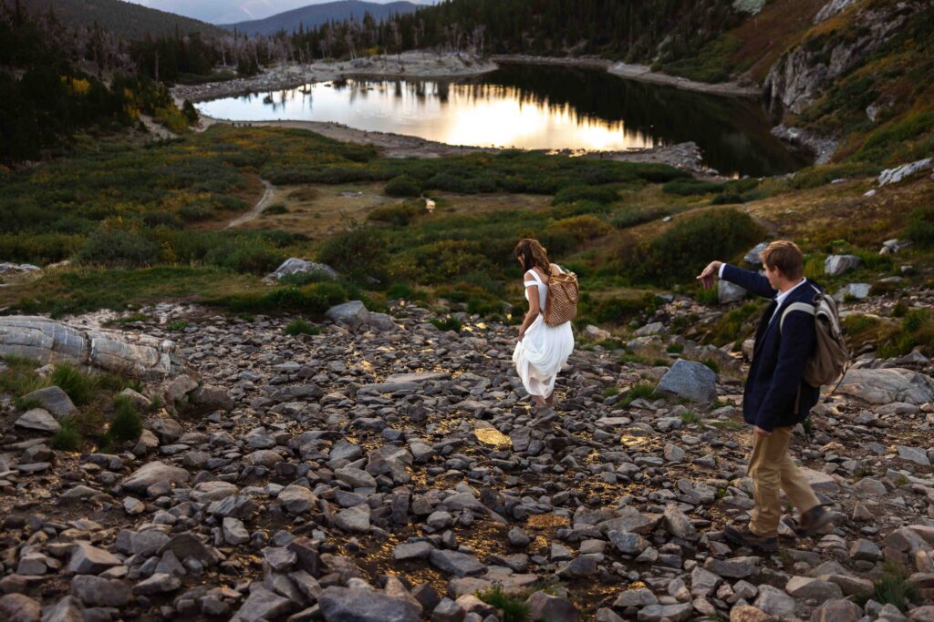 Couple standing on a rocky ledge, overlooking the glacial lake with arms wrapped around each other.