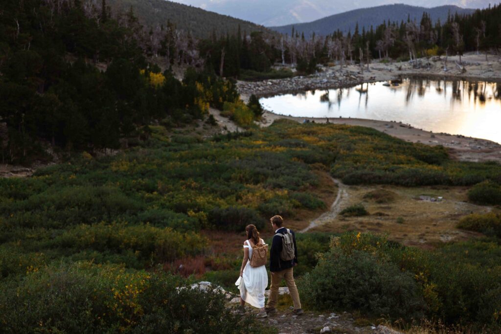 Epic wide-angle shot of the couple standing between towering pine trees on the hike up.