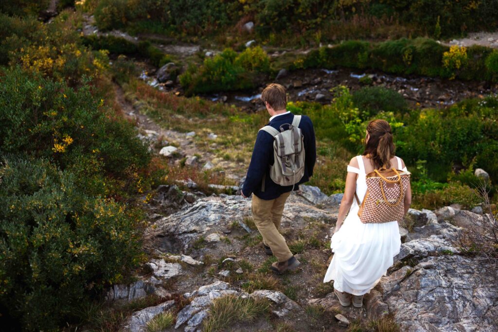 Bride looking over her shoulder with a big smile as she hikes toward the ceremony spot.