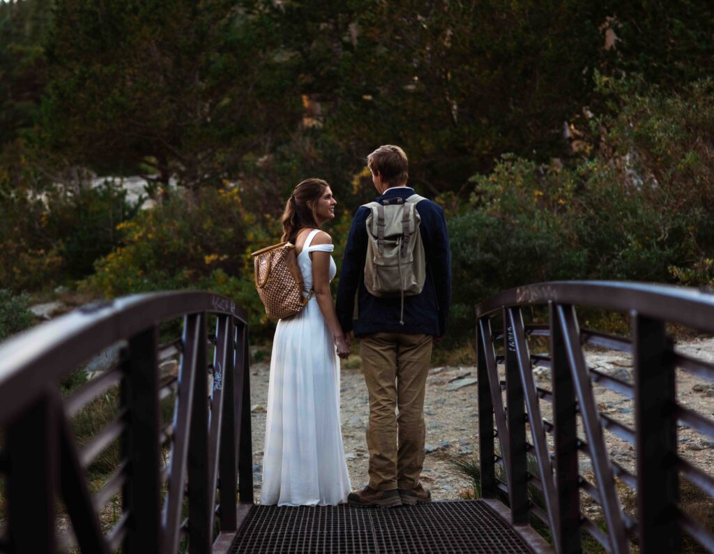 Wide shot of the couple standing on a boulder, overlooking the breathtaking mountain scenery.