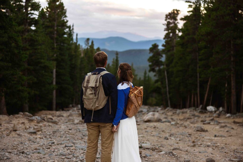 Close-up of the couple’s intertwined fingers, showcasing their wedding rings against the rugged landscape.