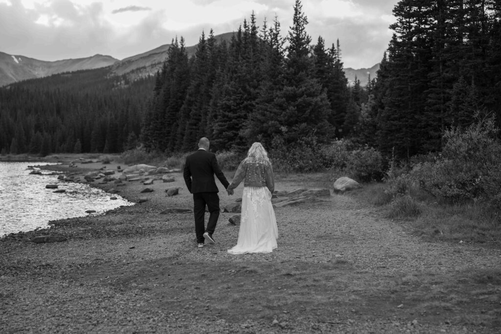 Couple walking hand in hand along a lakeside trail.