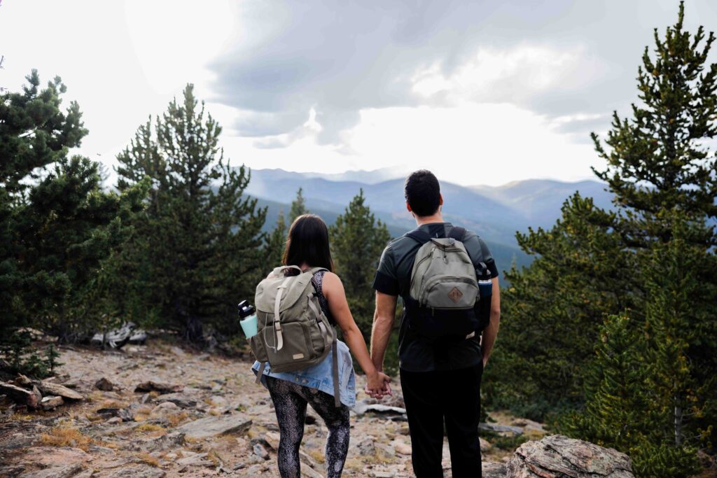 Couple hiking up the Chief Mountain trail, surrounded by stunning alpine views.