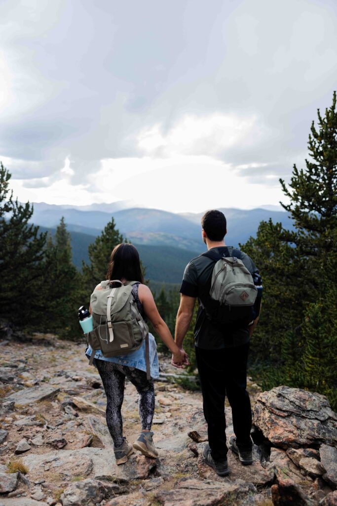 Bride and groom trekking through the mountain path with their wedding attire packed in backpacks.