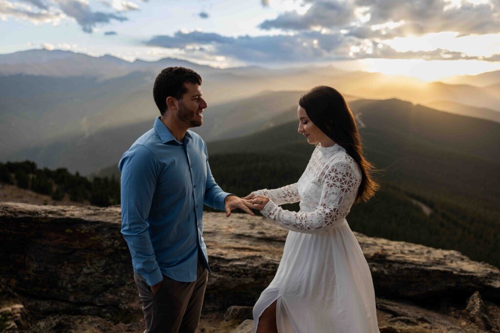 Newlyweds sitting on a rock ledge, enjoying a box of donuts after their vows.