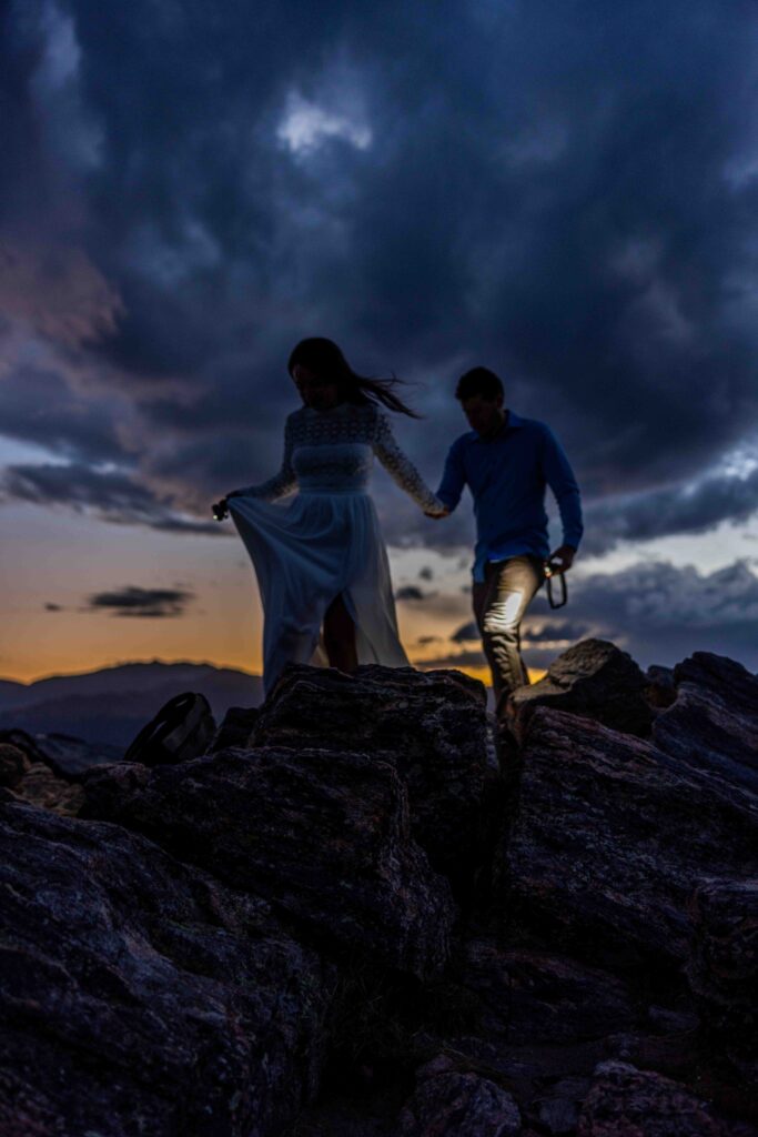 Golden-hour portrait of the couple embracing against a panoramic mountain view.