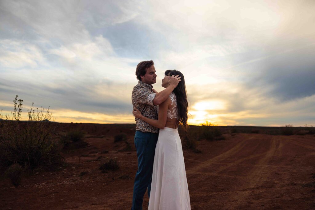 Couple popping a champagne bottle in the desert to celebrate