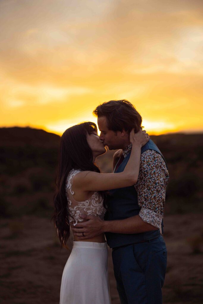 Sunset silhouette of the couple holding hands in the desert