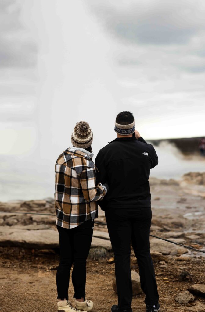 Couple embracing in front of a powerful Icelandic waterfall