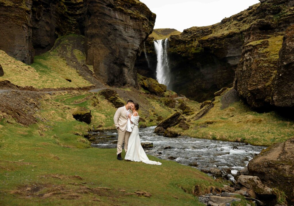 Groom lifting bride in celebration in front of a waterfall