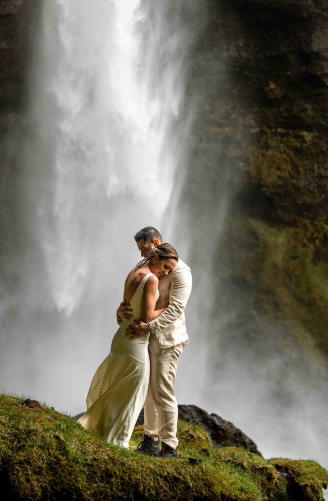 Bride standing on a rock while the groom gazes up at her