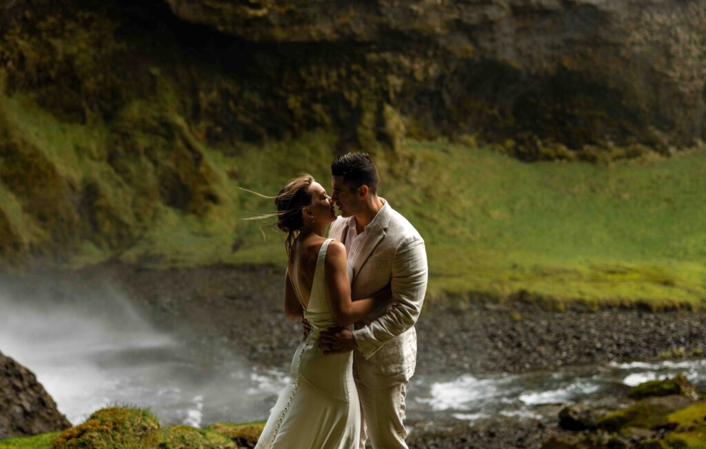 Newlyweds standing on a rocky cliffside overlooking the ocean