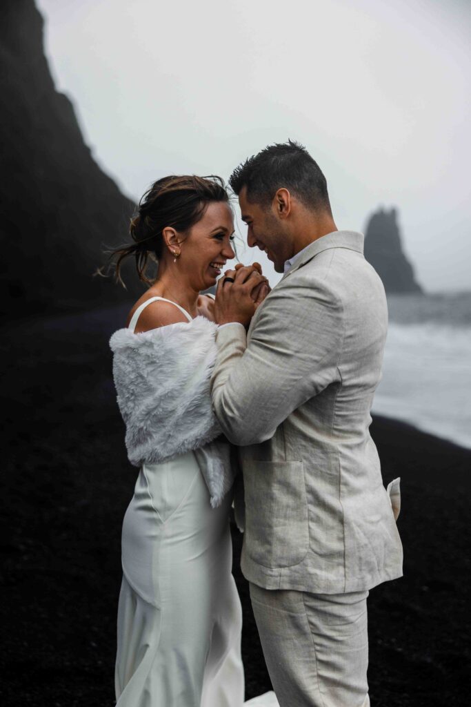 Bride holding her bouquet against the dark volcanic sand