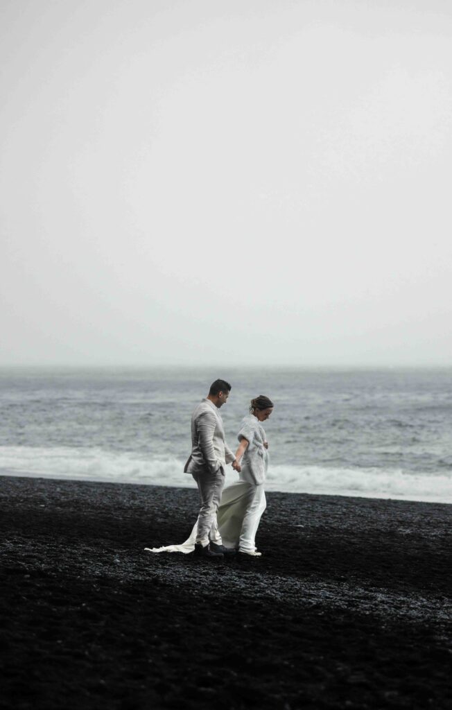 Couple running barefoot on the black sand beach