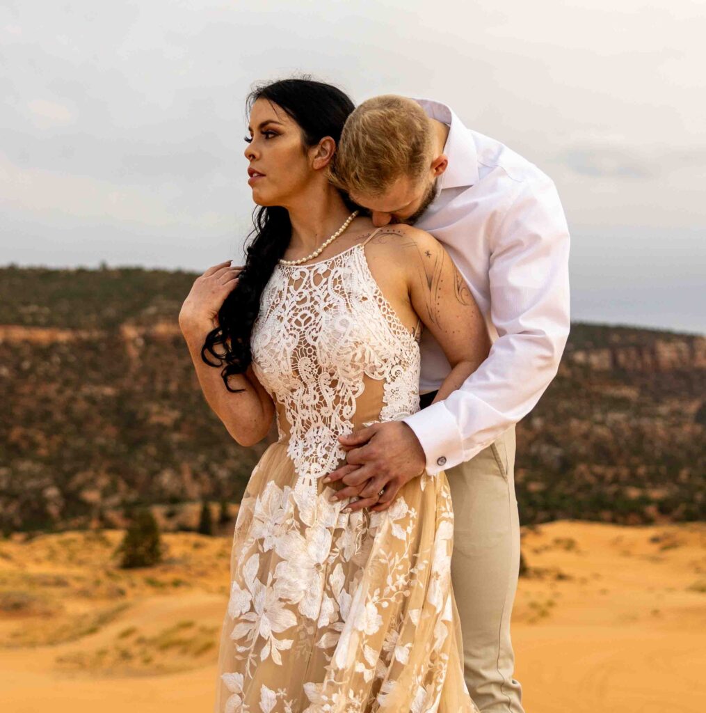 Bride’s wedding dress flowing in the wind against the soft desert landscape