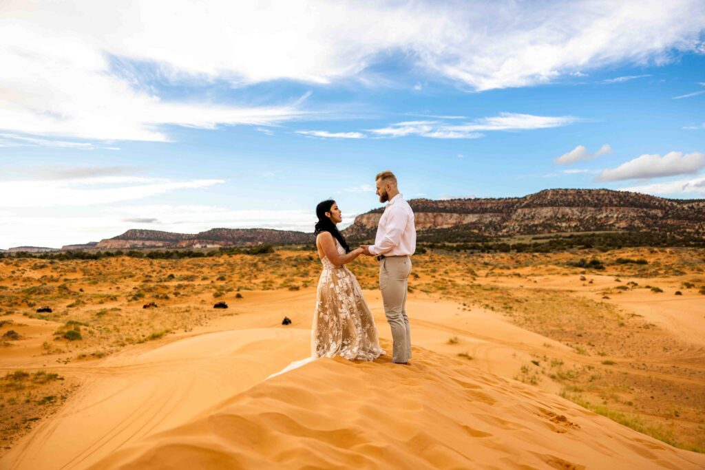 Soft-focus shot of hands intertwined with desert sand in the background