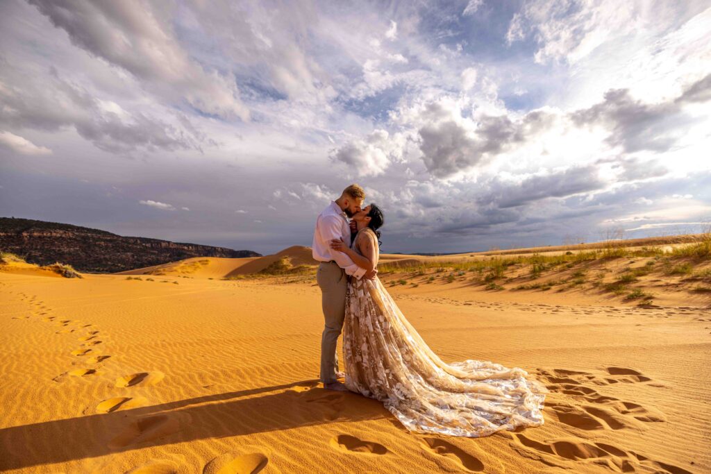 Aerial shot of the vast sand dunes with the couples standing together in the distance