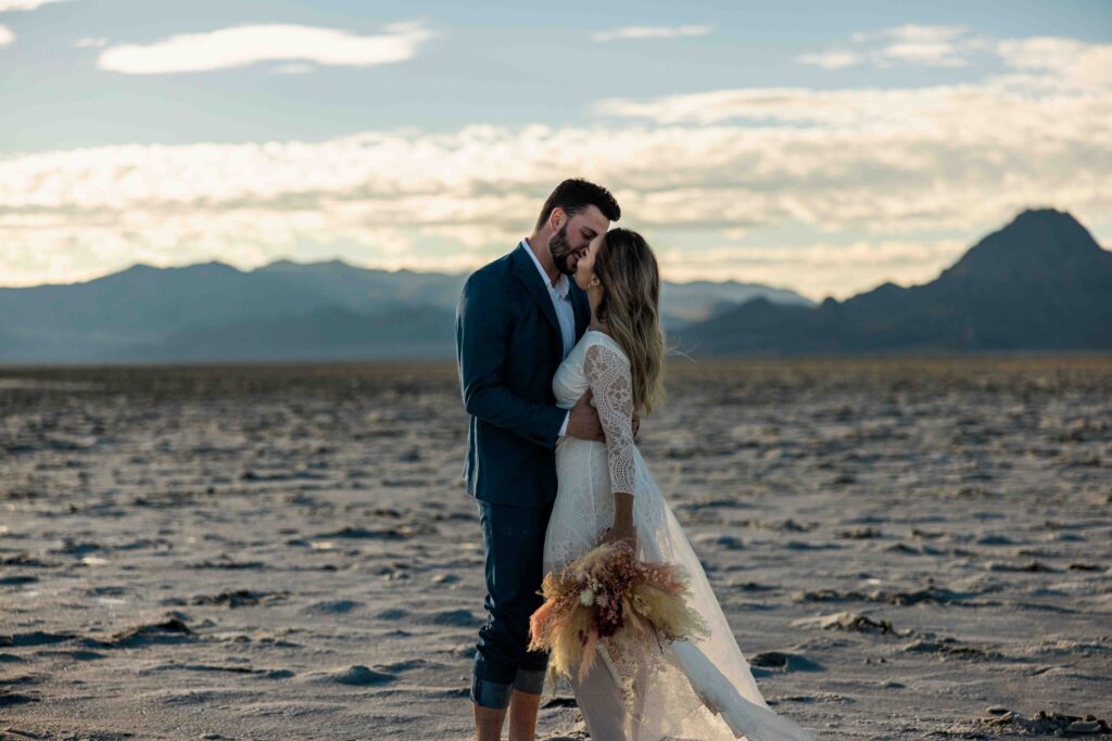 Wide-angle shot of the couple standing in the middle of the vast white salt flats