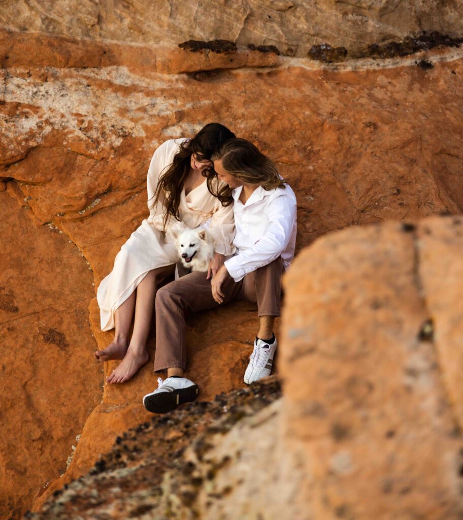 Close-up of the couple’s hands gripping the red sandstone as they ascend the cliffside.