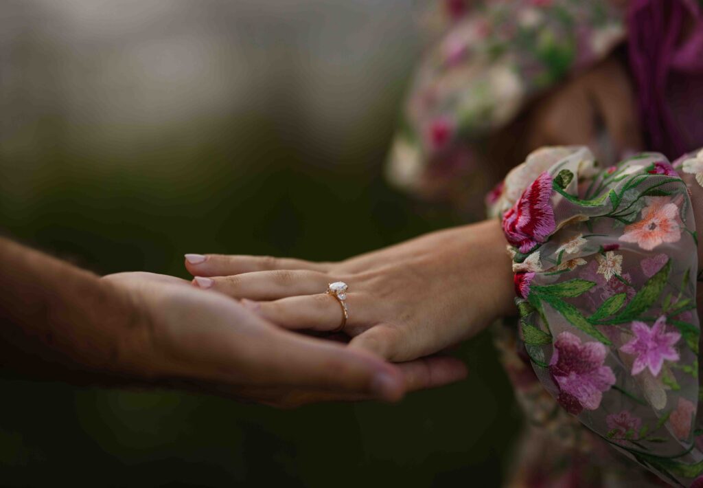 A close-up of the couple holding hands, highlighting the ring.