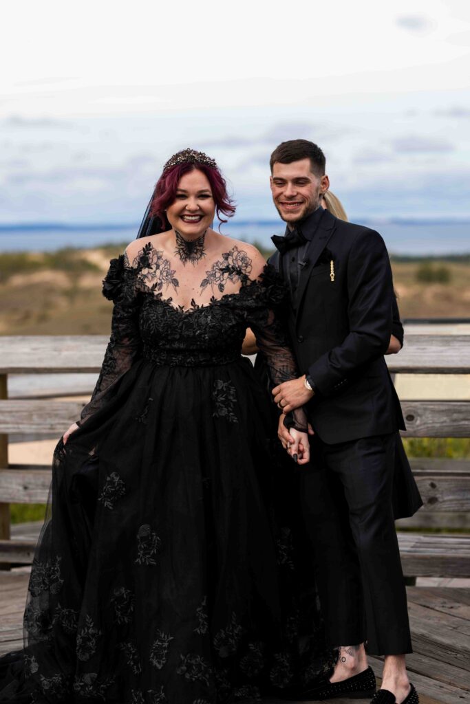 Bride and groom standing together with the dunes stretching behind them
