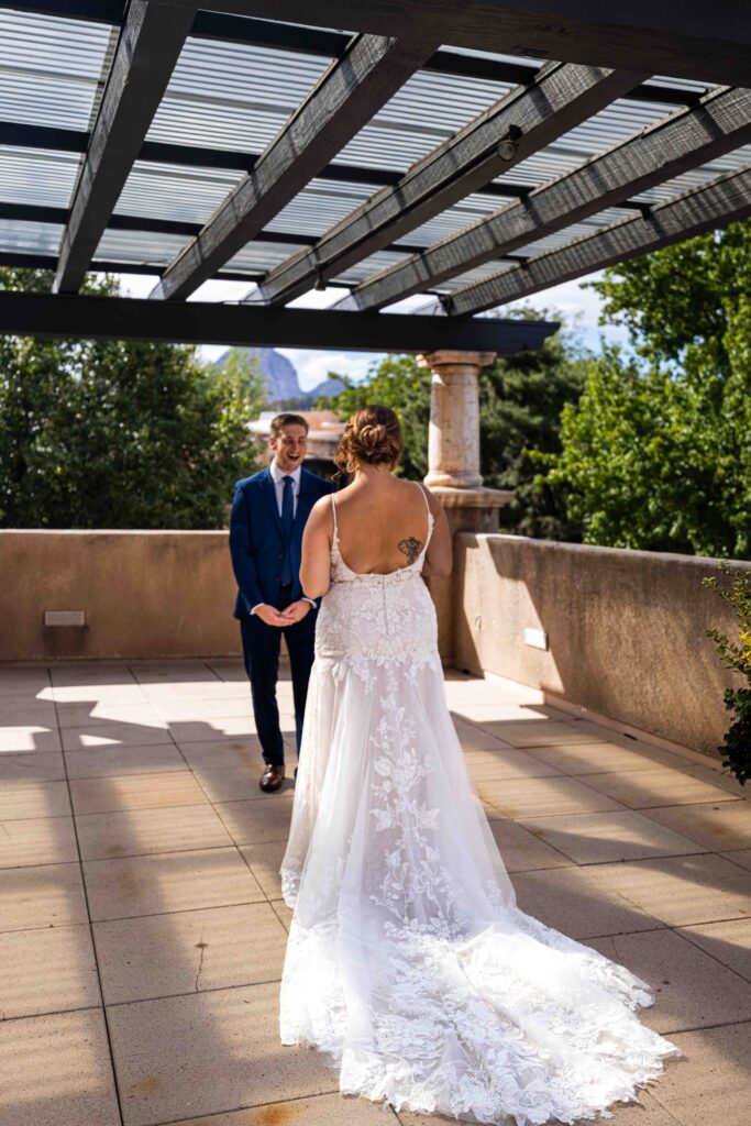 Couple standing under a Spanish-style archway, smiling at each other
