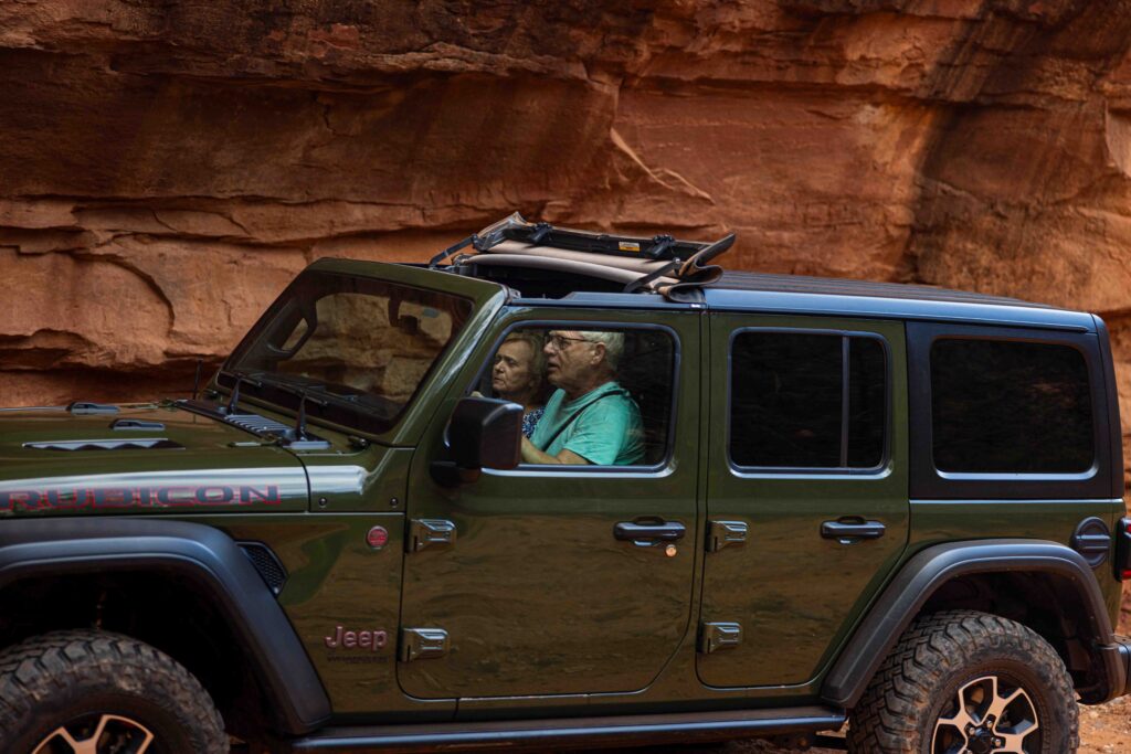 Bride and groom holding onto the Jeep’s roll bars, laughing as they enjoy the ride
