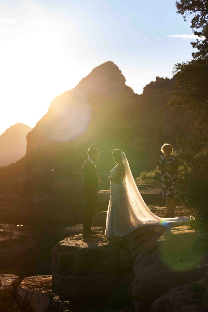 Couple standing at the edge of Merry Go Round Rock, with Sedona’s breathtaking landscape behind them
