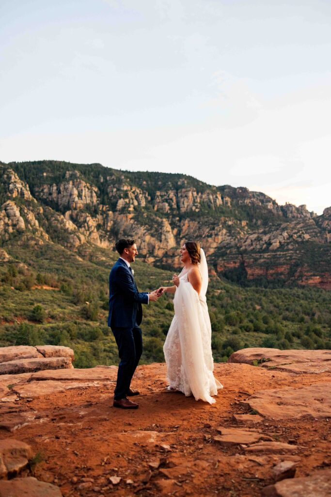 Bride’s veil blowing in the wind as the sun sets behind the red rocks
