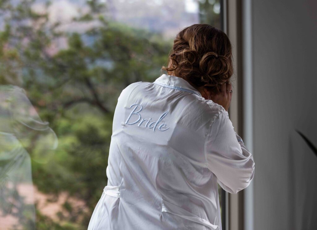 Bride applying mascara in front of an elegant vintage mirror
