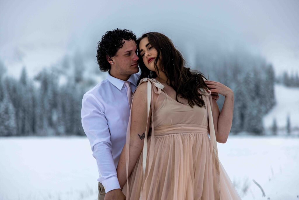 Bride and groom holding hands while trekking through fresh snowfall