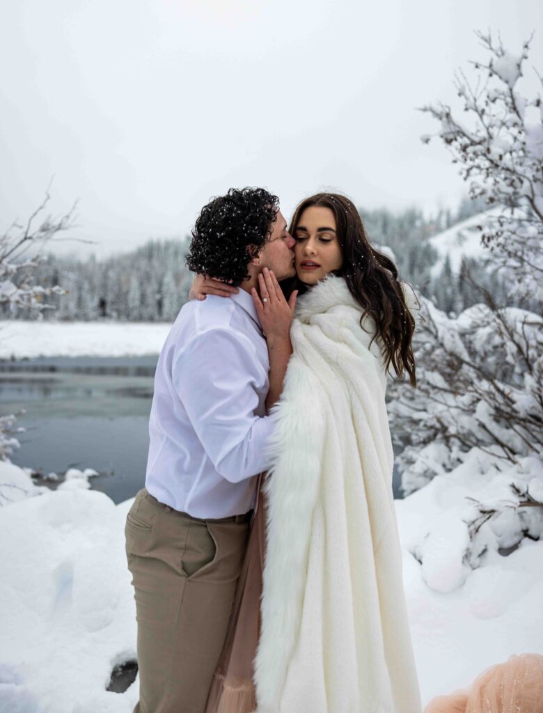 Bride wrapping herself in a cozy blanket while the groom hugs her