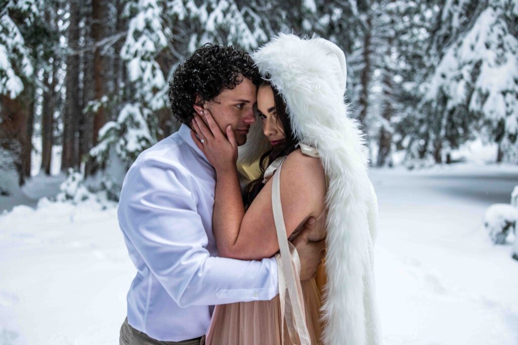 Couple dancing in the snow with a stunning mountain view behind them